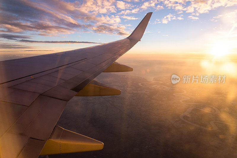机翼上的飞机在云海日落天空背景从窗口飞机