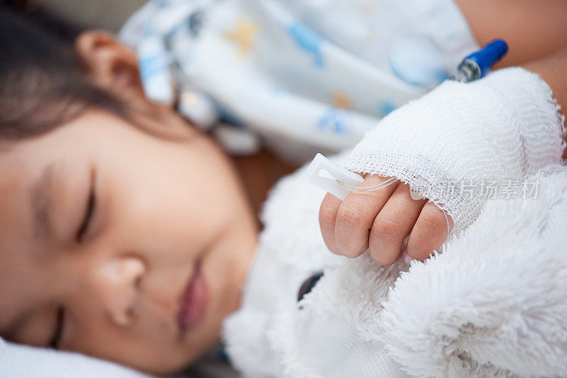 生病的小女孩用生理盐水的手在睡觉的时候抱着她的洋娃娃