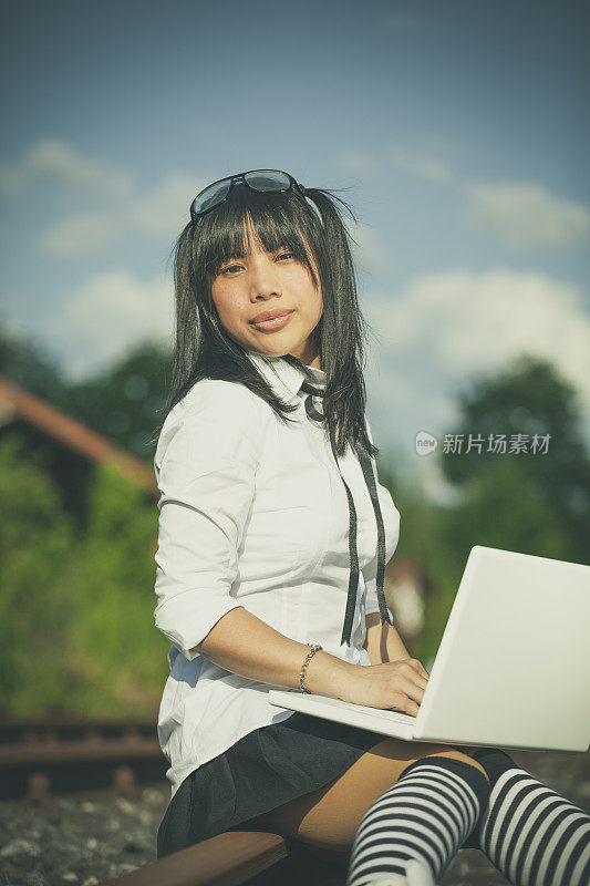 亚洲女学生在铁轨上用笔记本电脑
