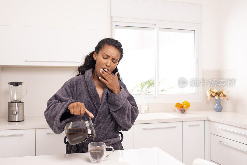 打哈欠的女人在早上倒咖啡。
