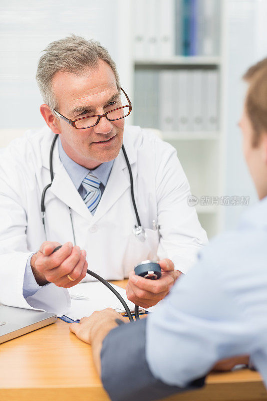 微笑成熟的医生给他的病人量血压