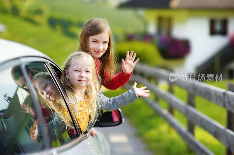 有趣的小女孩们把头伸出车窗，期待着一次公路旅行