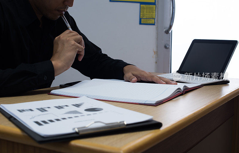商务人员在办公桌旁用数字平板电脑处理商务文件，后台绘制财务图表