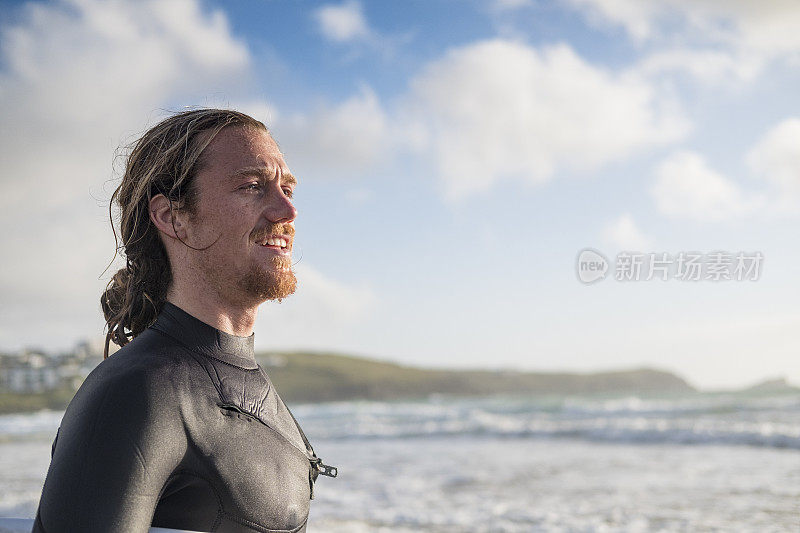 在费斯特拉海滩，纽基，康沃尔日落附近的冲浪者与冲浪板。