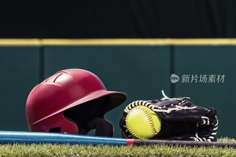 草地上一个戴着棒球帽和棒球棒的黄色垒球