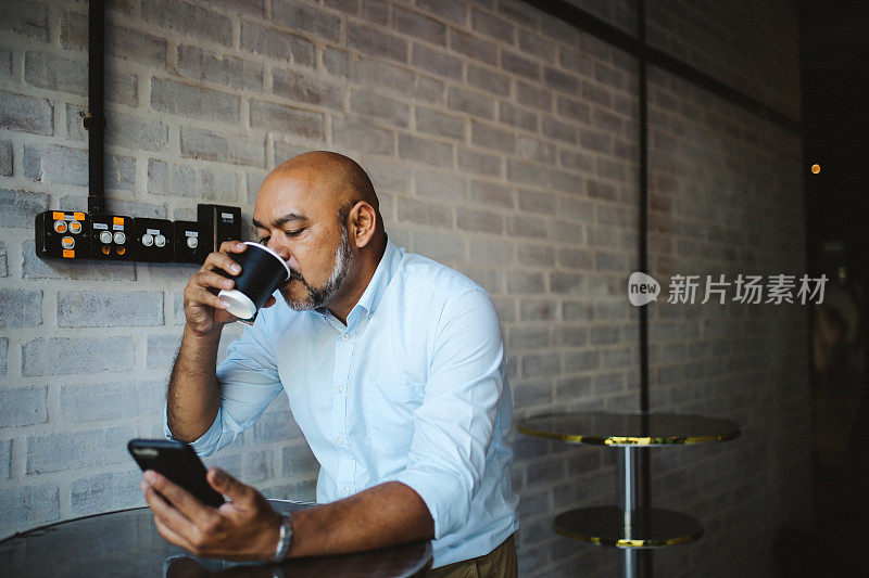 一名中年亚洲男子在吉隆坡的一家咖啡馆用手机发短信