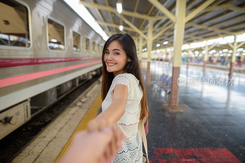 在泰国曼谷华兰蓬火车站，年轻美丽的亚洲女人牵着男人的手
