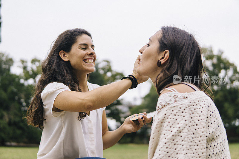 一对年轻女子在公园的户外化妆