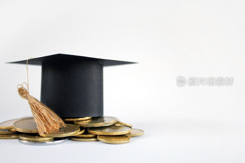 为概念金融和教育奖学金储蓄硬币的毕业上限。毕业文凭和金币上白色背景，概念投资教育，近距离，选择性聚焦，警察