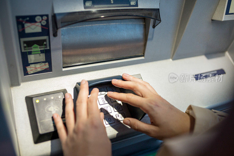 年轻女子将信用卡插入自动取款机