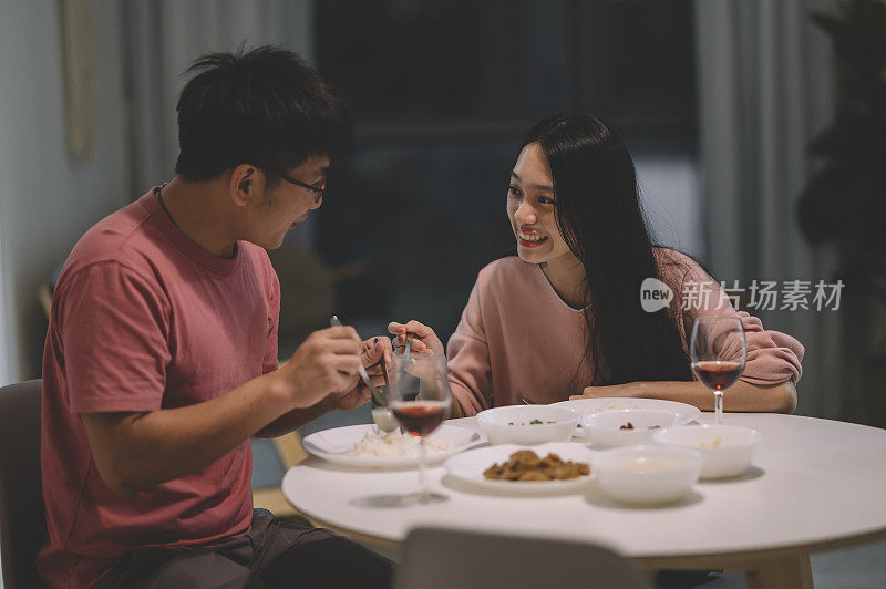 周末，一对亚洲华人夫妇在家里用红酒和中国菜共进晚餐