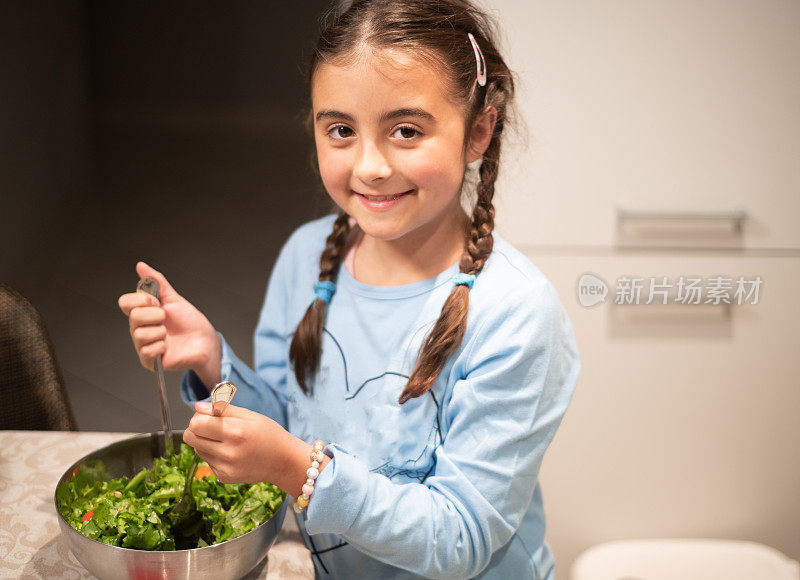 孩子们在厨房。小女孩正在为晚餐准备蔬菜沙拉