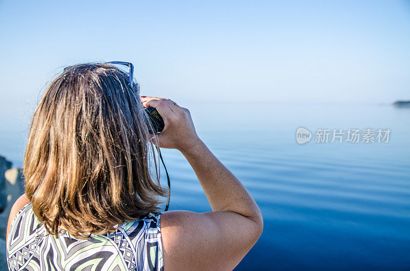 用双筒望远镜看海的女人