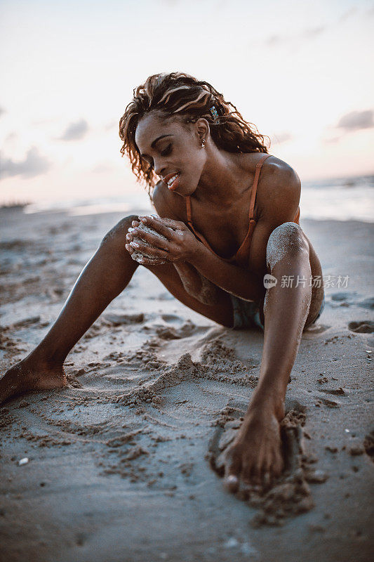 美丽的非洲女性在海滩上收集贝壳