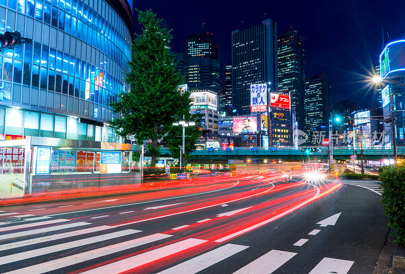 一些汽车在晚上经过新宿区日本最繁忙的十字路口之一