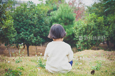 一个中国女孩坐在花园里的草地上