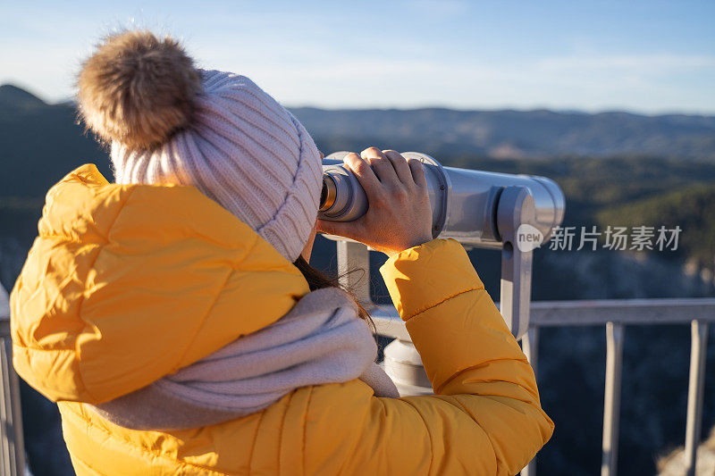 观点。独自旅行者在一个美丽的全景从高山上。冬天阳光明媚的户外享受。旅游目的地。用观光望远镜看。全景望远镜。