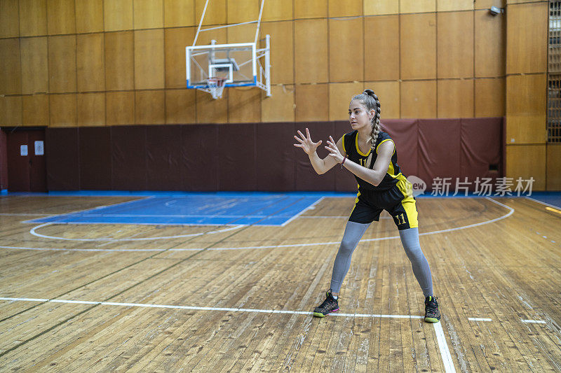 少女在学校礼堂练习篮球
