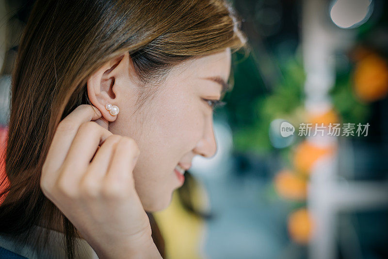 年轻的亚洲妇女在市集挑选耳环。