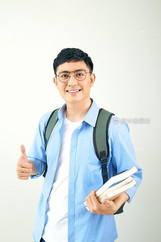 一个带着背包微笑的男学生的肖像，在白色的背景上竖起大拇指