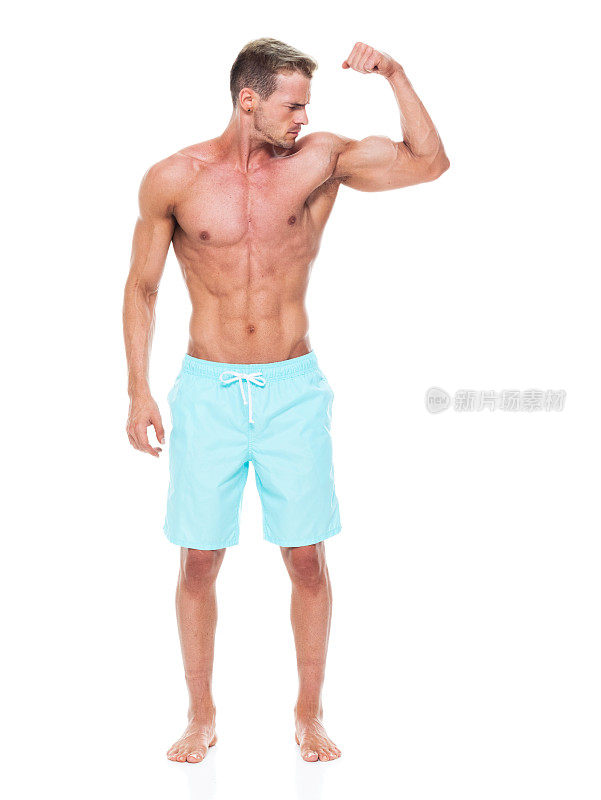 白人年轻男性运动员穿着短裤站在白色背景前，积极进行健身运动