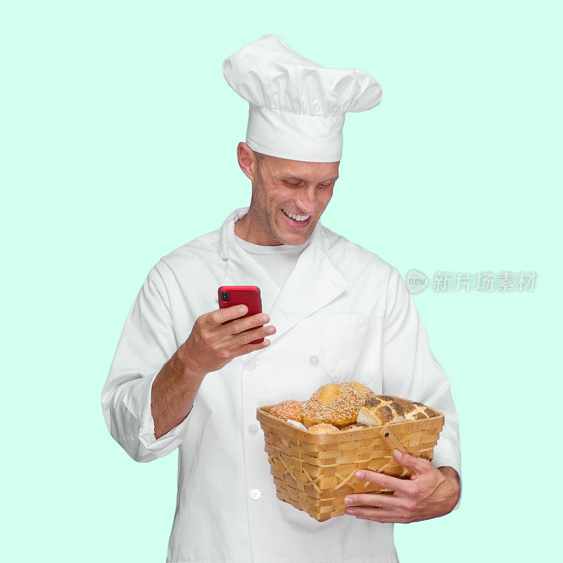 白人男性面包师站在有色背景前，穿着制服，拿着一条面包，使用短信