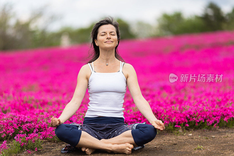 一位女士在粉红色的花田前沉思，享受户外的乐趣