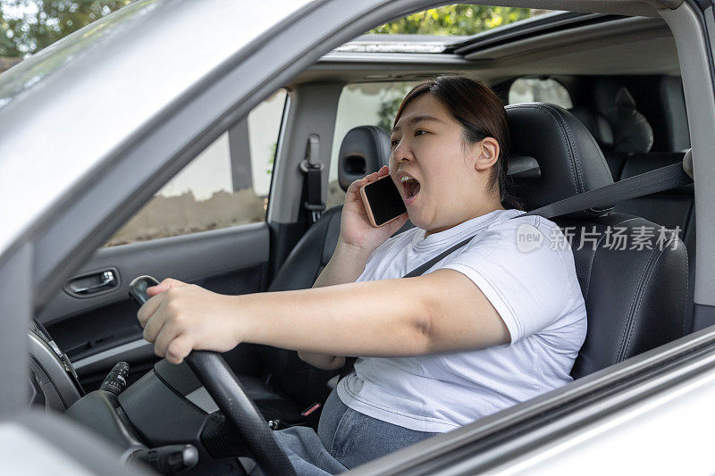 年轻女子一边开车一边打电话。