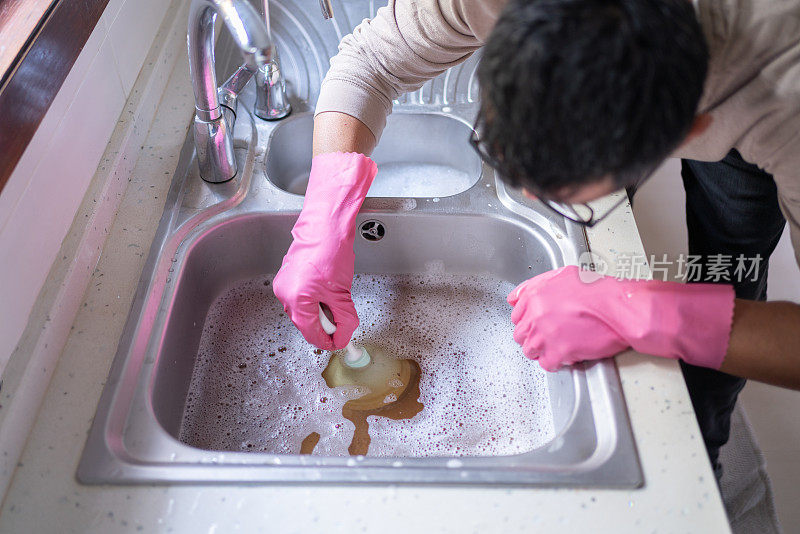 男子在厨房水槽里使用柱塞