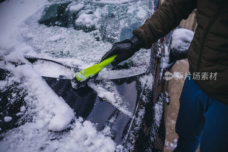 年轻人正在清除汽车上的积雪