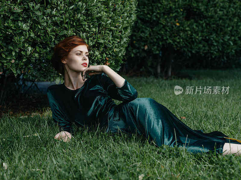 一个穿着绿色衣服的女人躺在仙女花园的草地上