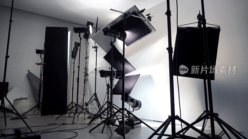 摄影棚内的灯光设置，用于商业作品，如照片电影或视频电影制作，使用许多1000瓦以上的LED灯，带有大软箱，防喷反射伞和三脚架。