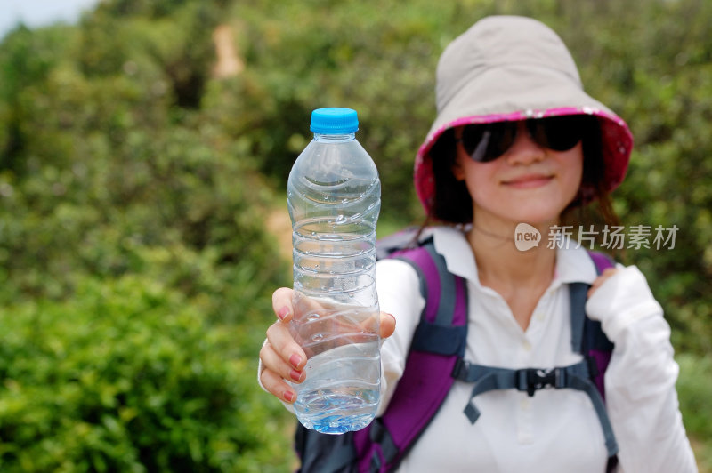 徒步旅行的年轻女子拿着一瓶水