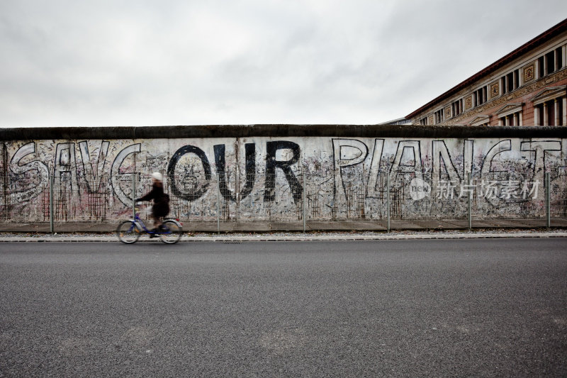 德国，东德，在柏林墙前骑自行车的女人