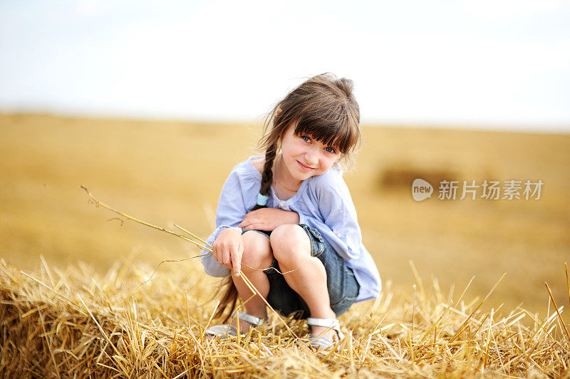 小女孩坐在草堆顶上