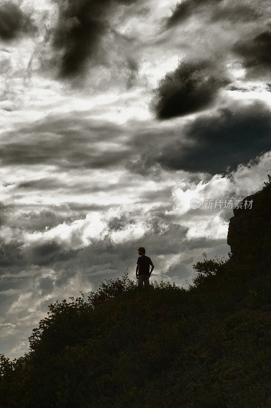 十几岁的男孩在山顶徒步旅行，那里有壮观的天空