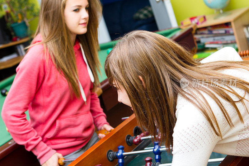 两个少女在青少年中心玩桌上足球