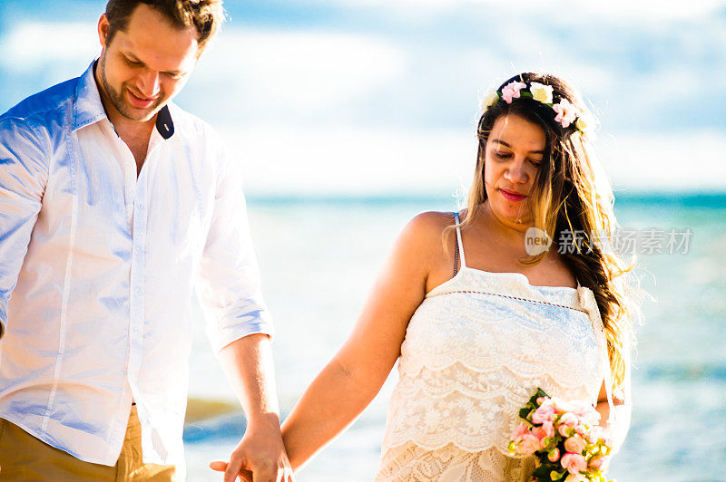 一对年轻的新婚夫妇在阳光明媚的海滩上相爱