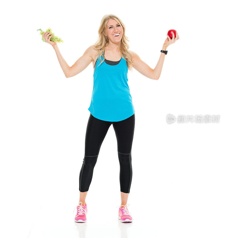 微笑的女运动员拿着苹果和葡萄