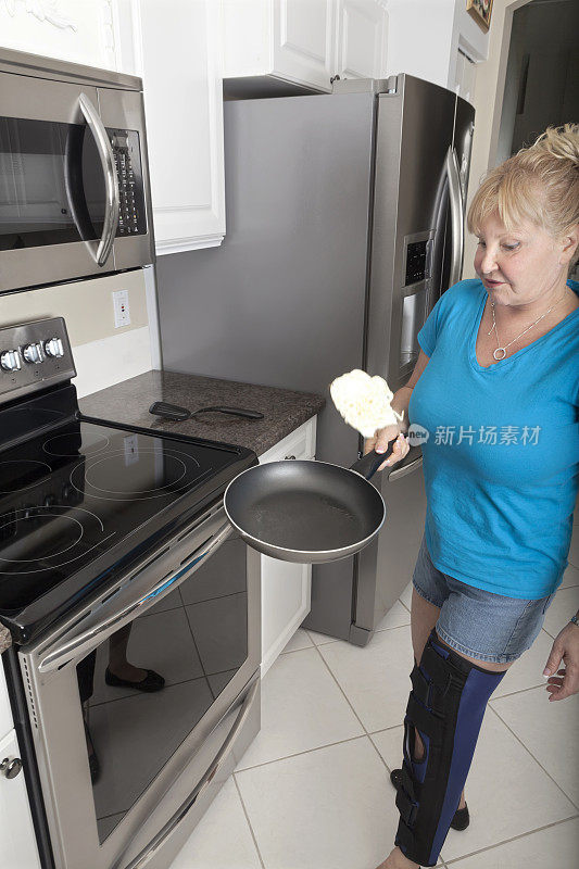 腿上打石膏的女人做饭