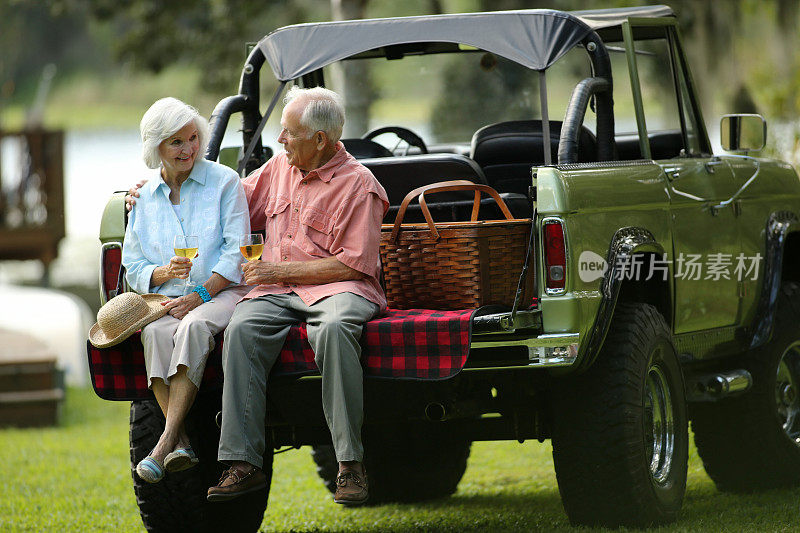相爱的老年夫妇在SUV车后面享受饮料