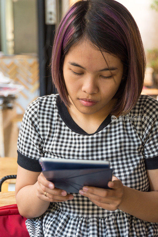 年轻的亚洲女人在用平板电脑上网