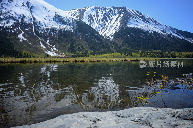 春天，阿拉斯加湖边的山上覆盖着积雪