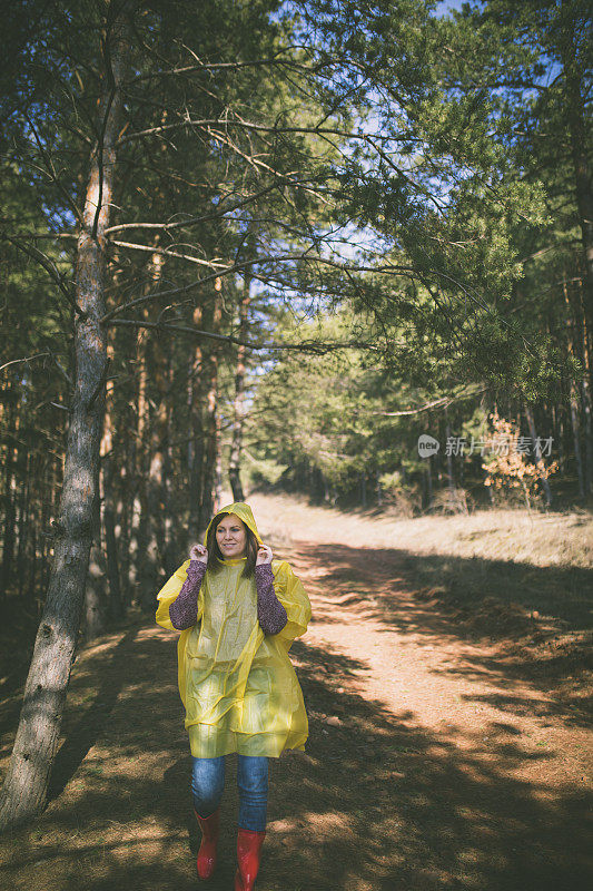 穿着雨衣的秋女在森林里行走