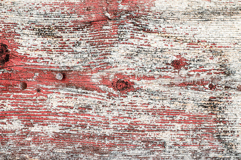木质纹理背景上旧的风化褪色的红色油漆剥落