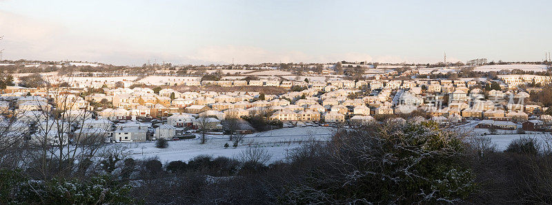 清晨的阳光洒在白雪覆盖的威尔士海滨小镇