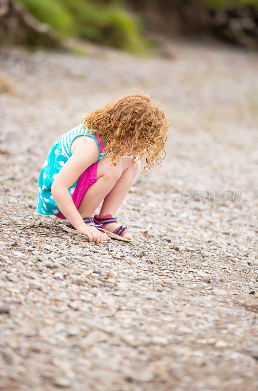 小女孩在河岸上捡石头