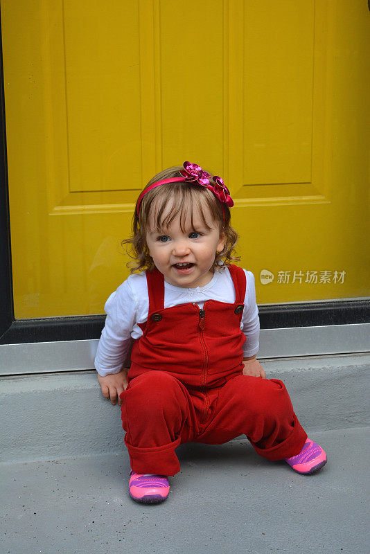 蓝眼睛金发小女孩穿着红色工装裤。