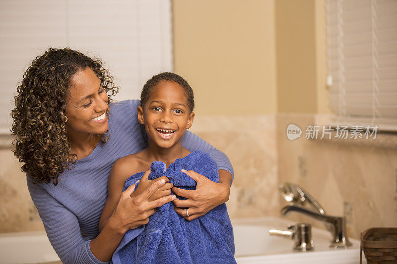 儿子洗澡后母亲把他擦干。家里的浴室。