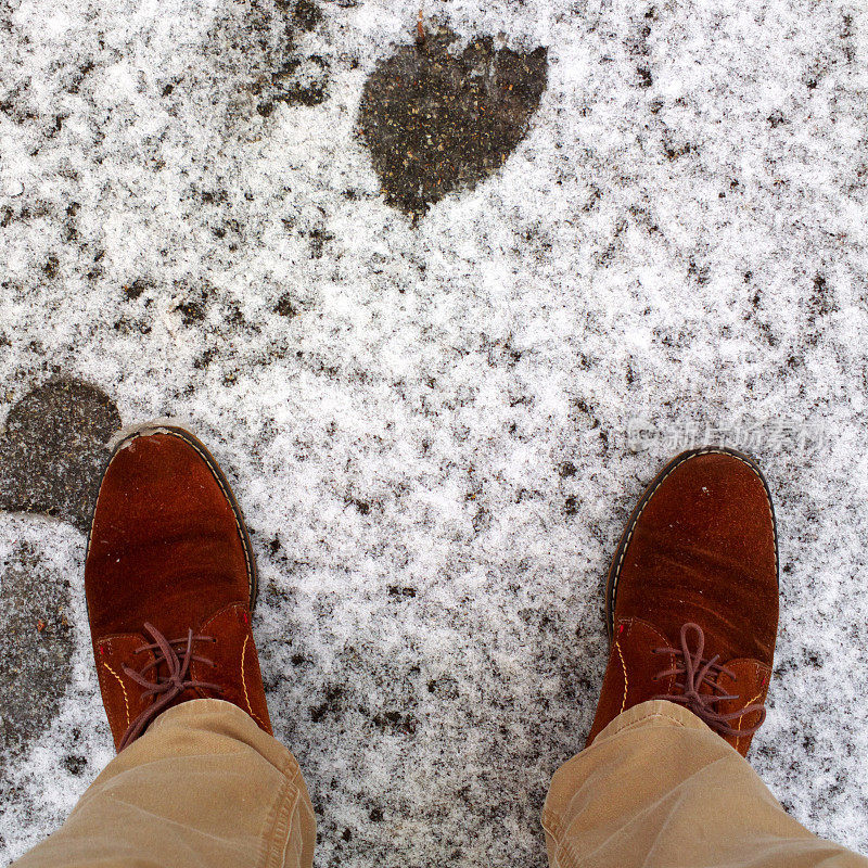 脚踩在雪地里的柏油路上。